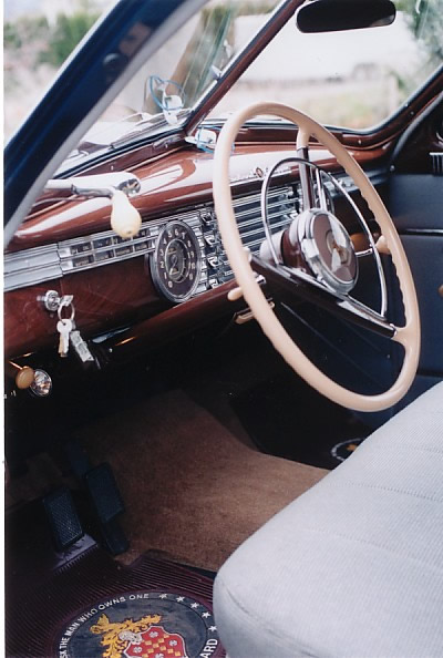 The Interior: note the simulated wood grained dash, ignition key on the left of the steering wheel and the special floor mats with Packard crest and slogan 'Ask the man who owns one'